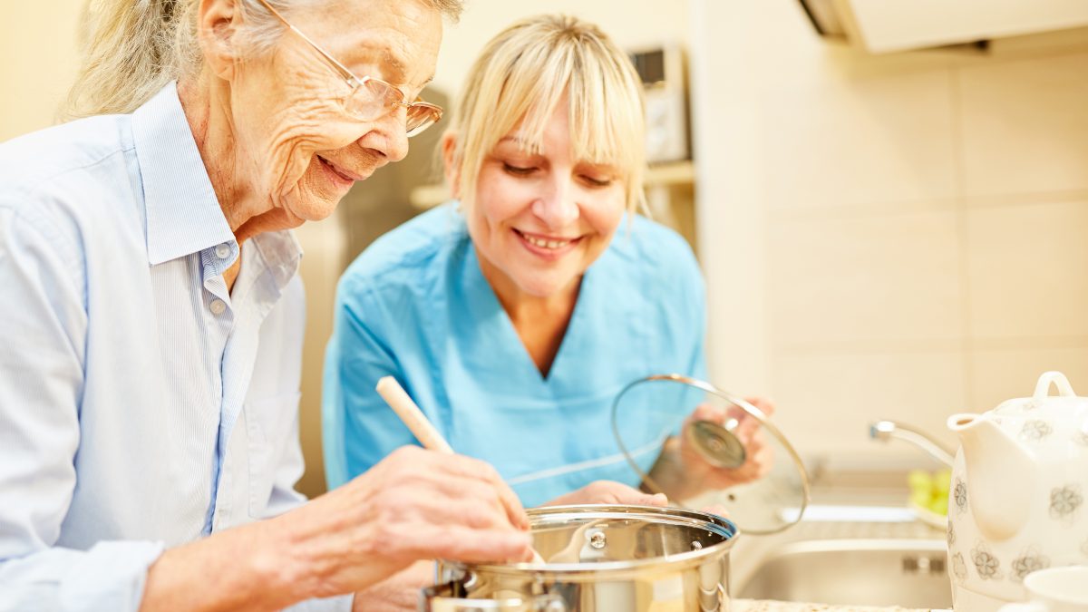 elderly cooking with caregiver assistance